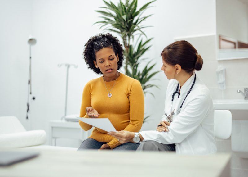 Female patient and doctor discussing test results in medical office.