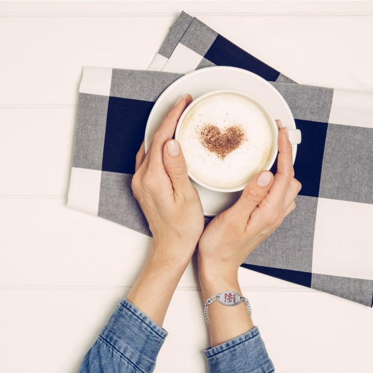 Women wearing the classic medical ID holding a coffee cup with heart shaped foam