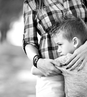 A sad boy hugging his mother