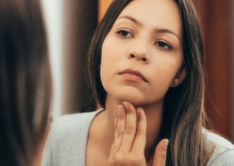A woman performing a thyroid self-check exam