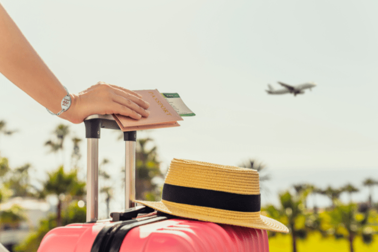 Tips for Traveling with a Chronic Medical Condition. Image: woman standing her hand on a pink suitcase as a plane flies by